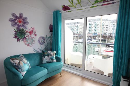 a living room with a blue couch and a large window at Chic apartment in the heart of Brighton Marina in Brighton & Hove