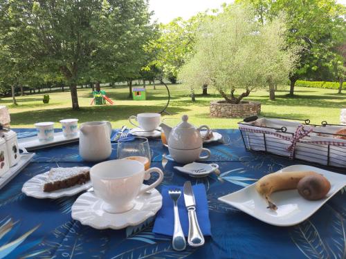 een blauwe tafel met theekopjes en een banaan erop bij Au Bonheur d'Angeline in Castelnaud La Chapelle