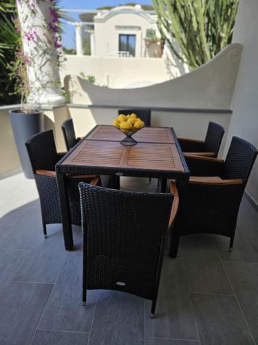 a wooden table and chairs with a bowl of fruit on it at Il Portico B&B Capri in Capri