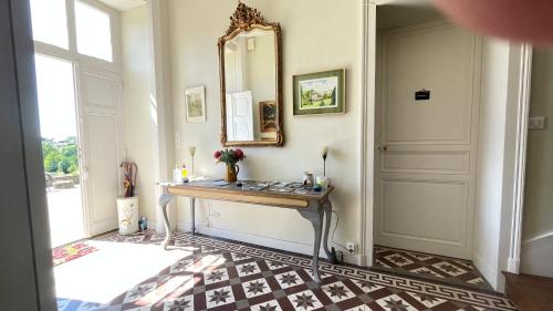 a hallway with a table and a mirror on the wall at Le Clos de Paris in Fresnay-sur-Sarthe