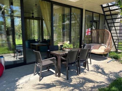 a patio with chairs and a table and a swing at Nina's house & Yard 200m from beach Kaprovani in Ureki