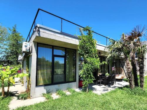 a house with large glass windows and a patio at Nina's house & Yard 200m from beach Kaprovani in Ureki