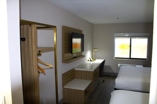 Schlafzimmer mit einem Bett, einem Schreibtisch und einem TV in der Unterkunft Baymont Inn & Suites by Wyndham San Marcos in San Marcos