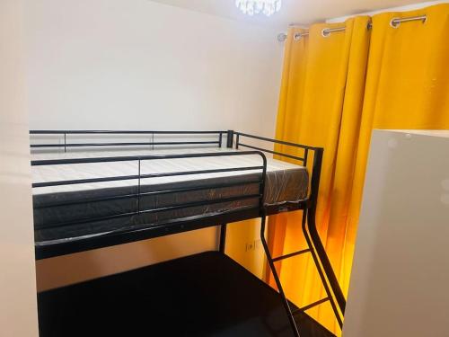 Ce lit superposé se trouve dans un dortoir doté d'un rideau jaune. dans l'établissement Appartement 2 chambres meublé, à Corbeil-Essonnes