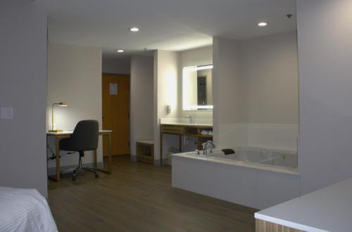 a bathroom with a sink and a bed and a desk at Baymont Inn & Suites San Marcos in San Marcos