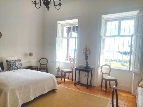 a bedroom with three chairs and a bed and windows at Villa Margaretha in Badacsonytomaj