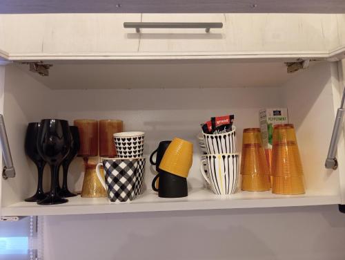 a shelf filled with different colored vases and cups at Black Diamond Lux - deluxe riverside apartment in Senta