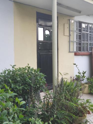 a black door on a white house with plants at Nam Garden in Kisumu