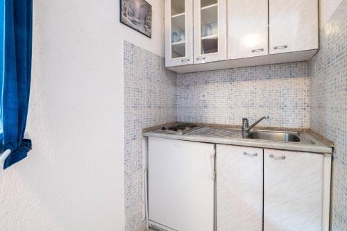 a small kitchen with white cabinets and a sink at Villa Nikola in Neum