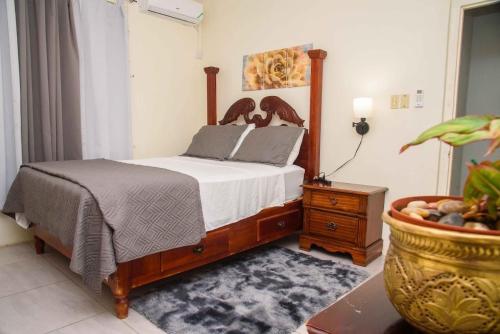 a bedroom with a bed and a table with a plant at Tranquil Oasis in Mona in Kingston