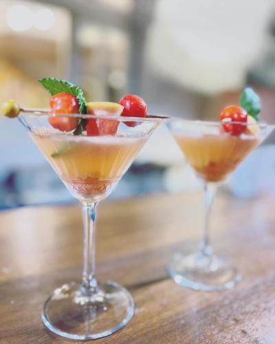 two martinis sitting on a wooden table with fruit in them at GREEN LORD DOMAINE - Lodges Piscine & Spa - Bar & Lounge - Restaurant gastronomique in Lamentin