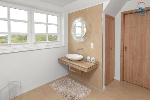 ein Badezimmer mit Waschbecken, Spiegel und Fenster in der Unterkunft Haus Seepferdchen 238 - Ferienhaus Watt in Juist
