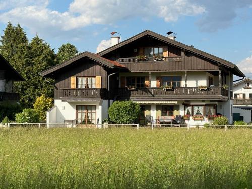 a large wooden house with a field in front of it at Ferienwohnung Alpina 1 in Wallgau