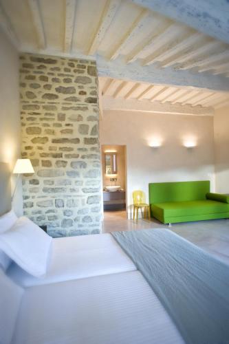 a bedroom with a green couch and a stone wall at Fondaco del Moro in Civitella in Val di Chiana