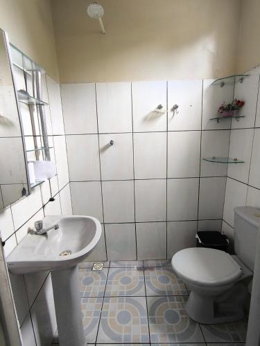 a white bathroom with a toilet and a sink at Quartos Econômicos in Manaus