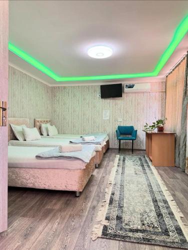 a room with two beds and a tv in it at Hotel GOLDEN DEGREZ in Bukhara