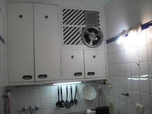 una cocina con armarios blancos y utensilios. en Libertador en Buenos Aires