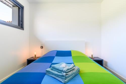 - une chambre avec un lit coloré et des serviettes dans l'établissement Superbe Villa au calme avec piscine, à Pontenx-les-Forges