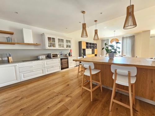 a kitchen with white cabinets and a large island with bar stools at Stunning Seafront Portomaso Apartment in Paceville
