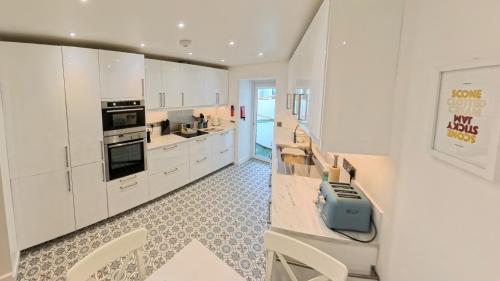 cocina con armarios blancos e impresora azul en Darracott Farm Cottage, en Welcombe