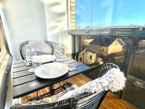 a table with plates and wine glasses on a balcony at Iso luksushuoneisto Forssan kattojen yllä in Forssa