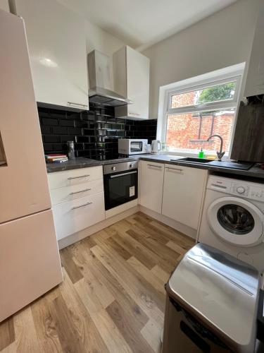 a kitchen with white cabinets and a washer at Alexandra Apartment -Secured Parking -2 Bedrooms in Crewe