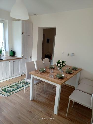 a dining room with a wooden table and white chairs at Gawlasoowka in Inwałd