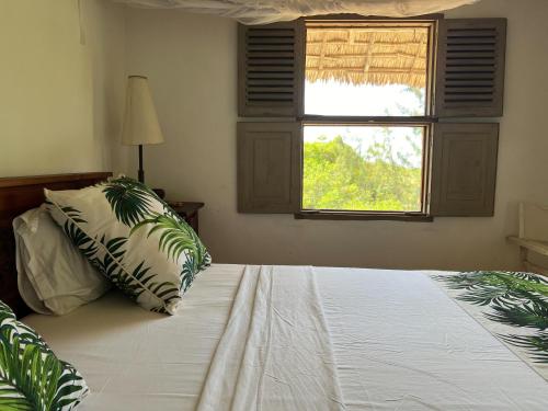 a bedroom with a bed with a pillow and a window at The Cabanas Lamu in Lamu