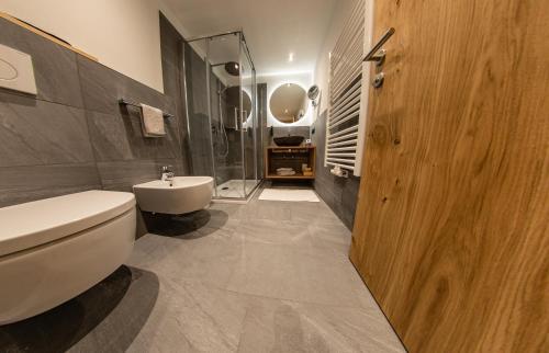 a bathroom with a white toilet and a sink at Hotel Gruber in Sesto