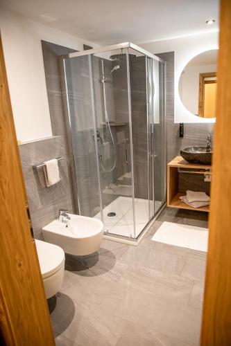 a bathroom with a shower and a toilet and a sink at Hotel Gruber in Sesto
