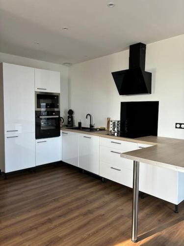 une cuisine avec des appareils blancs et un parquet dans l'établissement Appartement proche de la gare, à Rodez