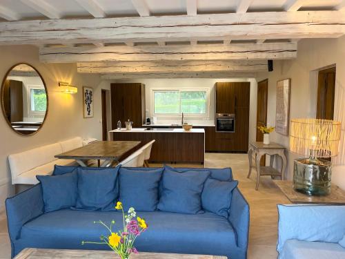 a living room with a blue couch and a kitchen at Les Restanques De Beaudine in Forcalquier