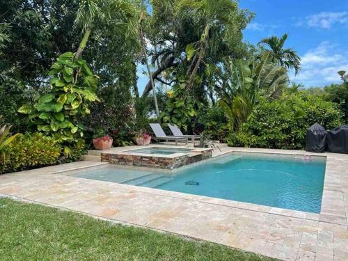 a swimming pool in a yard with a bench next to it at Villa Viscayne - Miami Modern Luxury with Pool & Spa in Biscayne Park