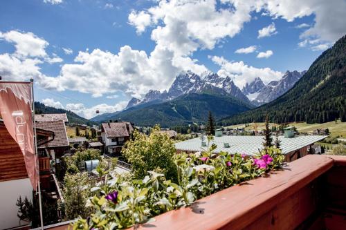 a view of mountains from a balcony with flowers at Hotel Gruber in Sesto