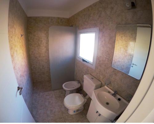 ein Badezimmer mit einem WC, einem Waschbecken und einem Spiegel in der Unterkunft Complejo de Cabañas Coquena in San Antonio de Arredondo