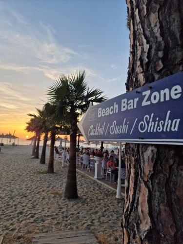 a beach bar zone sign on a beach with palm trees at Villa Pearl Adriatic Coast 2 in Golem