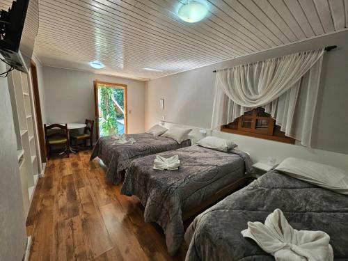 Habitación de hotel con 3 camas y mesa en Hotel Pousada Cabana da Mata, en Gramado