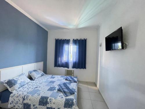 a bedroom with a bed and a tv on a wall at Pousada PÍER 22 in Caraguatatuba