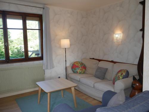 a living room with a white couch and a table at Gîte La Rose Jacuzzi Nordique in La Petite-Pierre