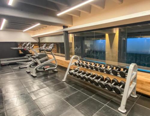 a gym with several rows of exercise equipment and a flat screen tv at Excelente! Vista al mar con cochera y amenities gimnasio, play room y pileta no climatizada in Mar del Plata