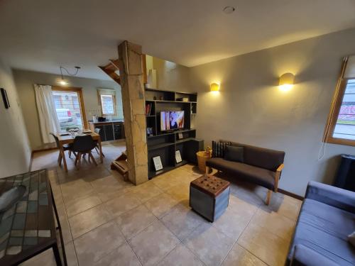 Una sala de estar con un sofá, un televisor y una mesa. en Paimun 2 - Andarlibre, en San Martín de los Andes