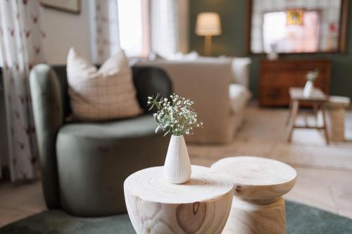 a white vase with flowers on two wooden tables in a living room at Boutiquehotel Ochsen in Lenzkirch