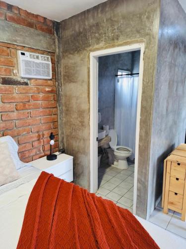 a bedroom with a brick wall and a bathroom at Rancho Matalote en Valle de Guadalupe in Valle de Guadalupe