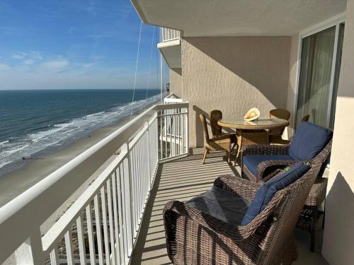 a balcony with chairs and a table and the ocean at Paradise at the Beach, Complete View of Horizon in Myrtle Beach