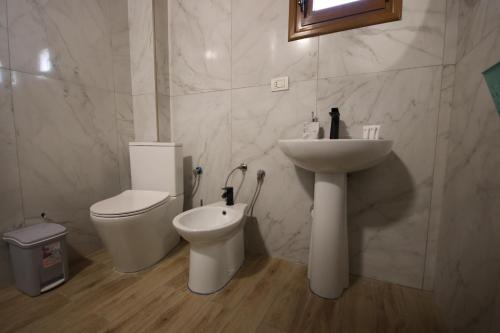 a white bathroom with a sink and a toilet at Vila Bajrami in Vlorë