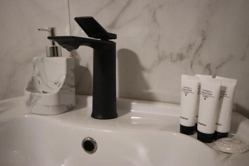 a bathroom sink with a black faucet and two toothbrushes at Vila Bajrami in Vlorë