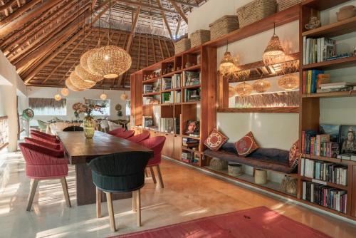 a dining room with a table and chairs and bookshelves at Hotel Casa Hormiga in Bacalar