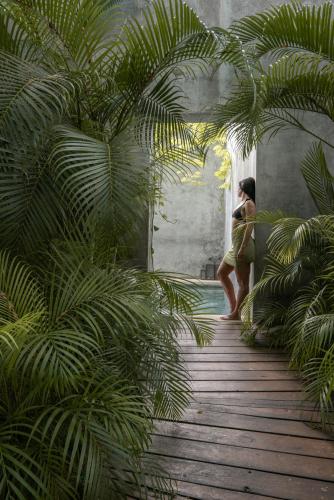 a woman standing on a wooden walkway with palm trees at Hotel Casa Hormiga in Bacalar