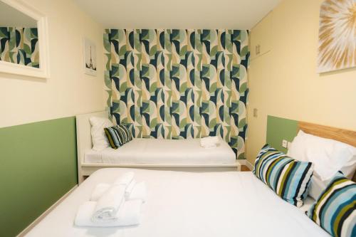 une petite chambre avec deux lits et un canapé dans l'établissement Stunning Modern Red Apartment near Bastille-Marais, à Paris