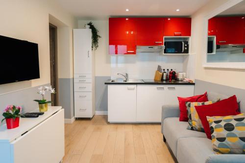 un salon avec un canapé et une cuisine avec des armoires rouges dans l'établissement Stunning Modern Red Apartment near Bastille-Marais, à Paris